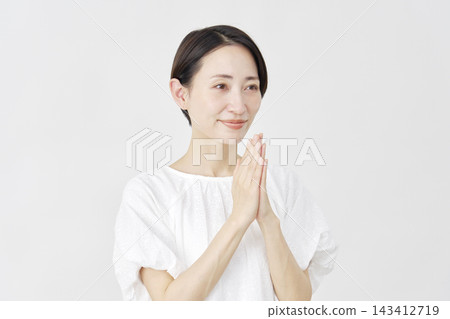 A middle-aged woman praying against a white background. A middle-aged woman praying against a white background. 143412719