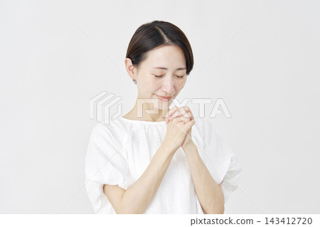 A middle-aged woman praying against a white background. A middle-aged woman praying against a white background. 143412720