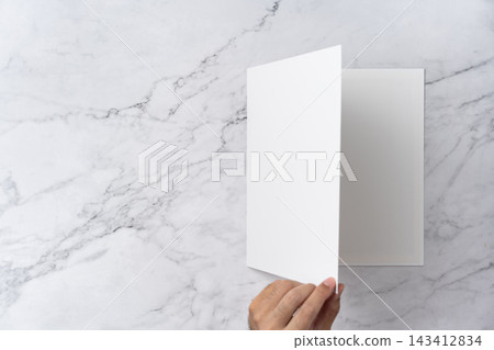 Top view sequence from open to close blank white greeting card mockup on marble background with copy space : hand opening a blank white folded greeting card 143412834