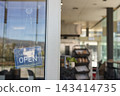 Yes WE'RE OPEN sign is hanging on glass door with dotted chain, blurred bakery interior 143414735