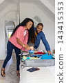 Couple wearing casual travel clothes packing suitcase on bed in loft bedroom with passport 143415353