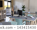 Central workstation table showing architectural plans on laptop and vertical monitor at studio 143415430