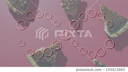 Glistening metallic-pink rings forming interlocking loops on dusty-pink mat, nut-filled pie slices 143421665