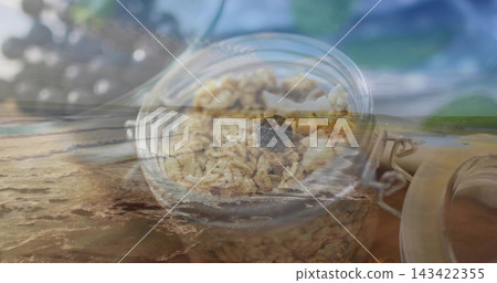 Layering glass jar with metal clamp holding granola clusters and single raisin over shoreline 143422355