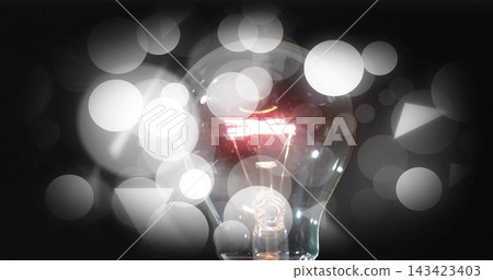Glowing incandescent bulb showing tungsten filament in studio, with glass glints and triangle bokeh Glowing incandescent bulb showing tungsten filament in studio, with glass glints and triangle bokeh 143423403