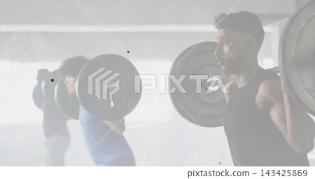 Squatting man wearing black tank top on gym floor, holding loaded barbell with plates, copy space 143425869
