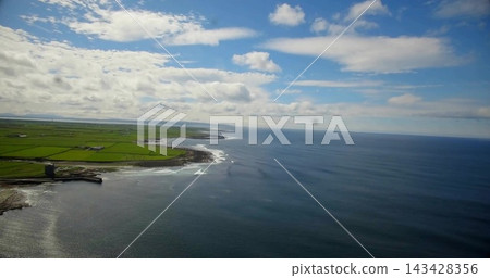 Showing coastal landscape with open ocean meeting rocky headland and stone tower, patchwork fields Showing coastal landscape with open ocean meeting rocky headland and stone tower, patchwork fields 143428356