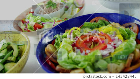 Showing blue salad bowl holding lettuce,tomato,onion,croutons on white tabletop with two bowls Showing blue salad bowl holding lettuce,tomato,onion,croutons on white tabletop with two bowls 143428443