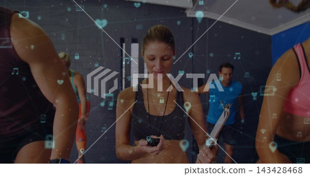 Leading female coach in tank top timing cardio in studio, holding stopwatch, clipboard, AR overlay 143428468
