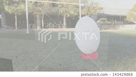 Standing white oval sculpture showing seam, resting on pink base on lawn with goalpost, copy space Standing white oval sculpture showing seam, resting on pink base on lawn with goalpost, copy space 143429868