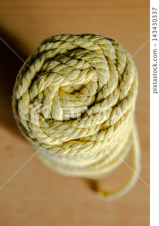 Coiled yellow rope on a wooden surface Coiled yellow rope on a wooden surface 143430337
