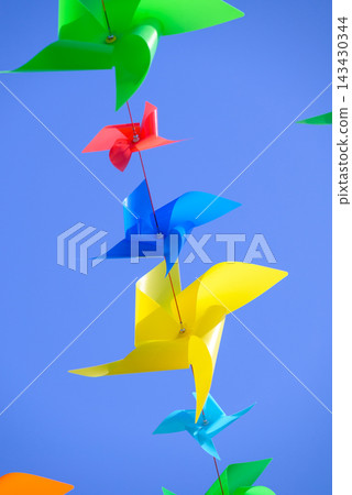 A vibrant upward view featuring colorful pinwheels against a clear blue sky. A vibrant upward view featuring colorful pinwheels against a clear blue sky. 143430344