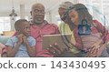 Watching family of four leaning on living room sofa, grandpa holding tablet, eyeglasses, padlock 143430495