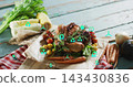 Showing roasted whole chicken on cutting board on blue tabletop with vegetables and teal eco icons 143430836