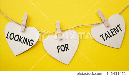 Looking For Talent text on wooden heart tags hanging on rope with clothespins over yellow background. Talent search and recruitment concept with copy space. 143431451