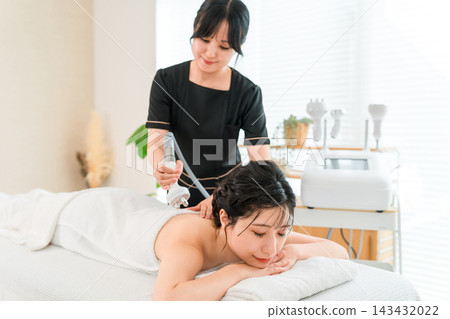 美容師正在美容院使用美容設備為顧客進行背部護理。 美容師正在美容院使用美容設備為顧客進行背部護理。 143432022