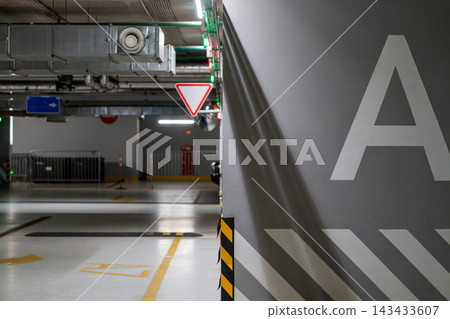 Empty Underground Parking Garage Interior With Concrete Pillar Marked A And Directional Signs 143433607