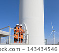 Wind turbine maintenance engineers using laptop on elevated platform inspection at wind farm 143434546