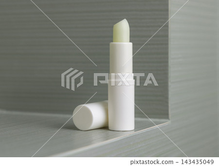 Open lip balm stick mockup with a lid in sage green bathroom. Herbal cosmetic product for daily use Open lip balm stick mockup with a lid in sage green bathroom. Herbal cosmetic product for daily use 143435049
