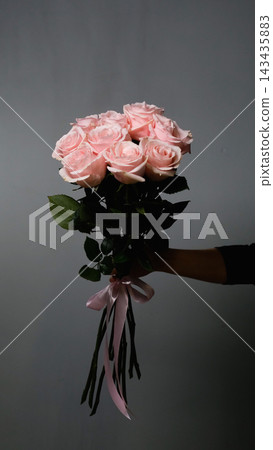 A florist creates a custom bouquet. Close-up of a bouquet of roses against a gray background. Beautiful pink roses at a flower shop. A florist creates a custom bouquet. Close-up of a bouquet of roses against a gray background. Beautiful pink roses at a flower shop. 143435883