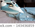 Close-up of a steam iron on a blue shirt, showing clothing maintenance, wrinkle removal and everyday garment care at home. 143436859