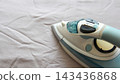 Steam iron pressing white fabric on a bed, showing garment care, wrinkle removal and everyday household ironing. 143436868