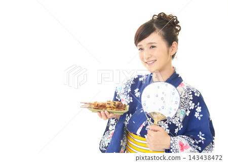 一位身穿浴衣的女子手捧烤雞串。 一位身穿浴衣的女子手捧烤雞串。 143438472
