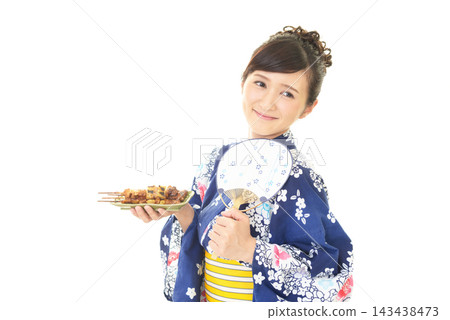 一位身穿浴衣的女子手捧烤雞串。 一位身穿浴衣的女子手捧烤雞串。 143438473