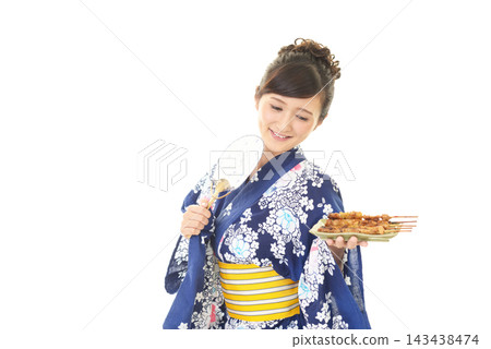 一位身穿浴衣的女子手捧烤雞串。 一位身穿浴衣的女子手捧烤雞串。 143438474