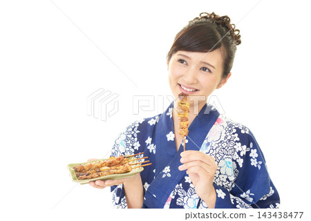 一位身穿浴衣的女子手捧烤雞串。 一位身穿浴衣的女子手捧烤雞串。 143438477