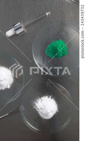 Chemistry lab experiment preparing chemical compounds using white and green powder on watch glass for scientific analysis Chemistry lab experiment preparing chemical compounds using white and green powder on watch glass for scientific analysis 143439732