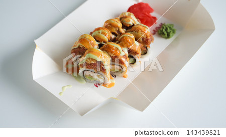 Sushi rolls with sauces and toppings in a delivery box, enjoying a Japanese takeaway meal at home 143439821