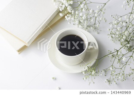 一本合上的書,一杯黑咖啡,還有一張擺放著滿天星的明亮桌子。 一本合上的書,一杯黑咖啡,還有一張擺放著滿天星的明亮桌子。 143440969