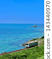 一列當地火車沿著藍色的海岸線行駛，天空湛藍，海岸線呈現美麗的夏日景色。 143440970