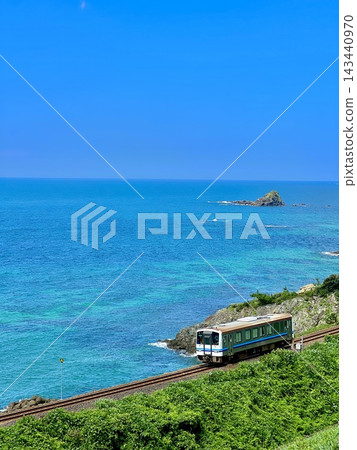 一列當地火車沿著藍色的海岸線行駛,天空湛藍,海岸線呈現美麗的夏日景色。 一列當地火車沿著藍色的海岸線行駛,天空湛藍,海岸線呈現美麗的夏日景色。 143440970