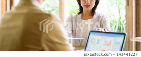A business person presenting documents in a meeting, along with a graph on their computer. A business person presenting documents in a meeting, along with a graph on their computer. 143441227