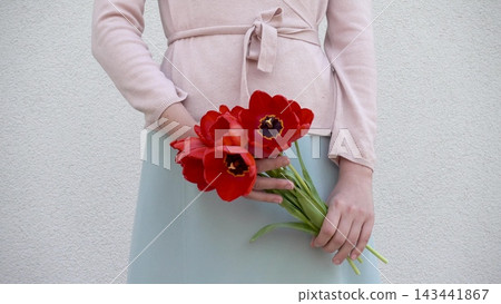 Cute woman holds a vibrant bouquet of red tulips Cute woman holds a vibrant bouquet of red tulips 143441867
