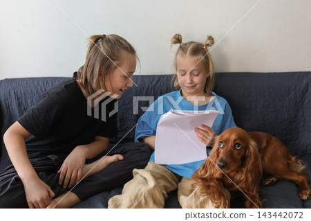 Adorable girl and boy sitting on blue sofa with dog red cocker spaniel indoors Adorable girl and boy sitting on blue sofa with dog red cocker spaniel indoors 143442072