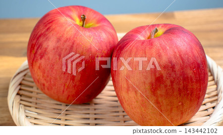 A photo of two Sun Tsugaru apples placed in a bamboo basket. A photo of two Sun Tsugaru apples placed in a bamboo basket. 143442102