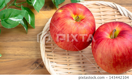 A photo of two Sun Tsugaru apples placed in a bamboo basket. 143442104