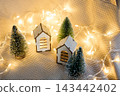 Cozy Christmas village with wooden miniature houses and fairy lights. 143442402