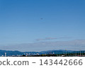 Small airplane flying in clear blue sky above a riverside city and green hills 143442666
