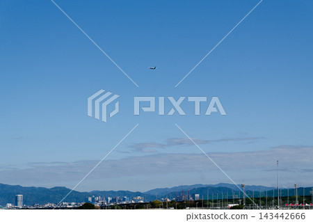 Small airplane flying in clear blue sky above a riverside city and green hills Small airplane flying in clear blue sky above a riverside city and green hills 143442666
