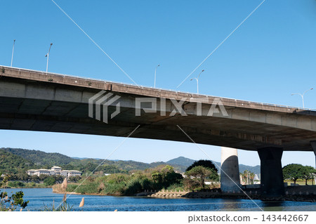 Concrete elevated bridge spanning a river under clear blue sky with green hills Concrete elevated bridge spanning a river under clear blue sky with green hills 143442667