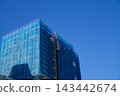 High-rise building under construction wrapped in blue safety netting 143442674