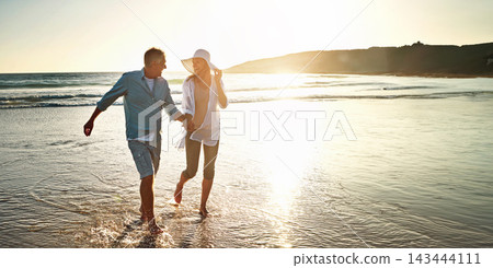 Happy couple, walking and beach for holiday on island or coast for getaway, travel and vacation in Bali. Woman, man and holding hands for love or marriage anniversary by ocean at sunset in Indonesia 143444111