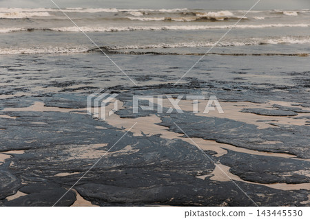Oil fuel contamination spreads across a beach, creating a serious environmental pollution disaster Oil fuel contamination spreads across a beach, creating a serious environmental pollution disaster 143445530