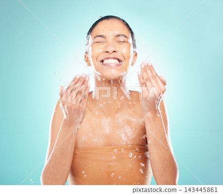 Skincare, water splash and woman washing face in studio for wellness, hygiene and skin health isolated on blue background. Beauty, cleaning and happy model in shower for dermatology and liquid bath Skincare, water splash and woman washing face in studio for wellness, hygiene and skin health isolated on blue background. Beauty, cleaning and happy model in shower for dermatology and liquid bath 143445861