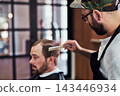 Hair care, customer and man in barbershop with comb, cut and tools for trendy hairstyle trim at small business. Style, barber and client in chair for grooming service, haircut skills and clean shave 143446934
