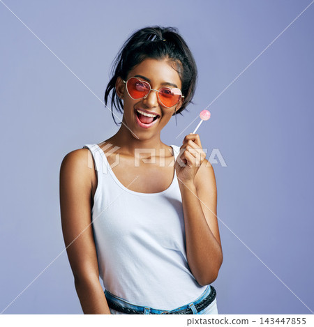 Girl, lollipop and smile with sunglasses in studio on purple background in casual, style and elegant. Portrait, fashion and excited with happy for eyewear or street wear, outfit and confident Girl, lollipop and smile with sunglasses in studio on purple background in casual, style and elegant. Portrait, fashion and excited with happy for eyewear or street wear, outfit and confident 143447855